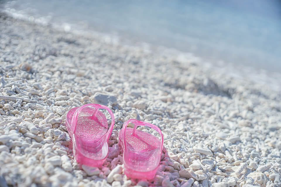 宮古島観光のイメージ写真。ビーチとピンク色のギョサン