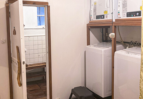 つるみ荘の共有シャワー室入口前無料の洗濯機・乾燥機の写真